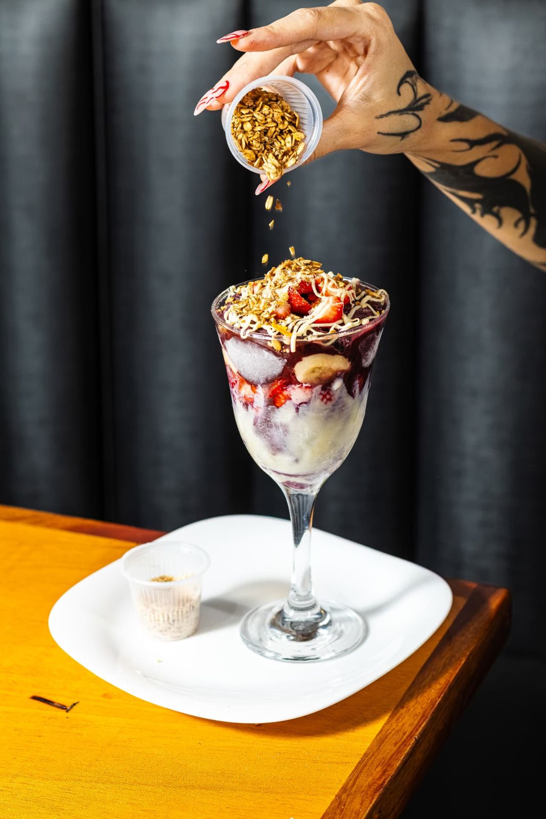 Açaí na taça recebendo granola, com morango e banana