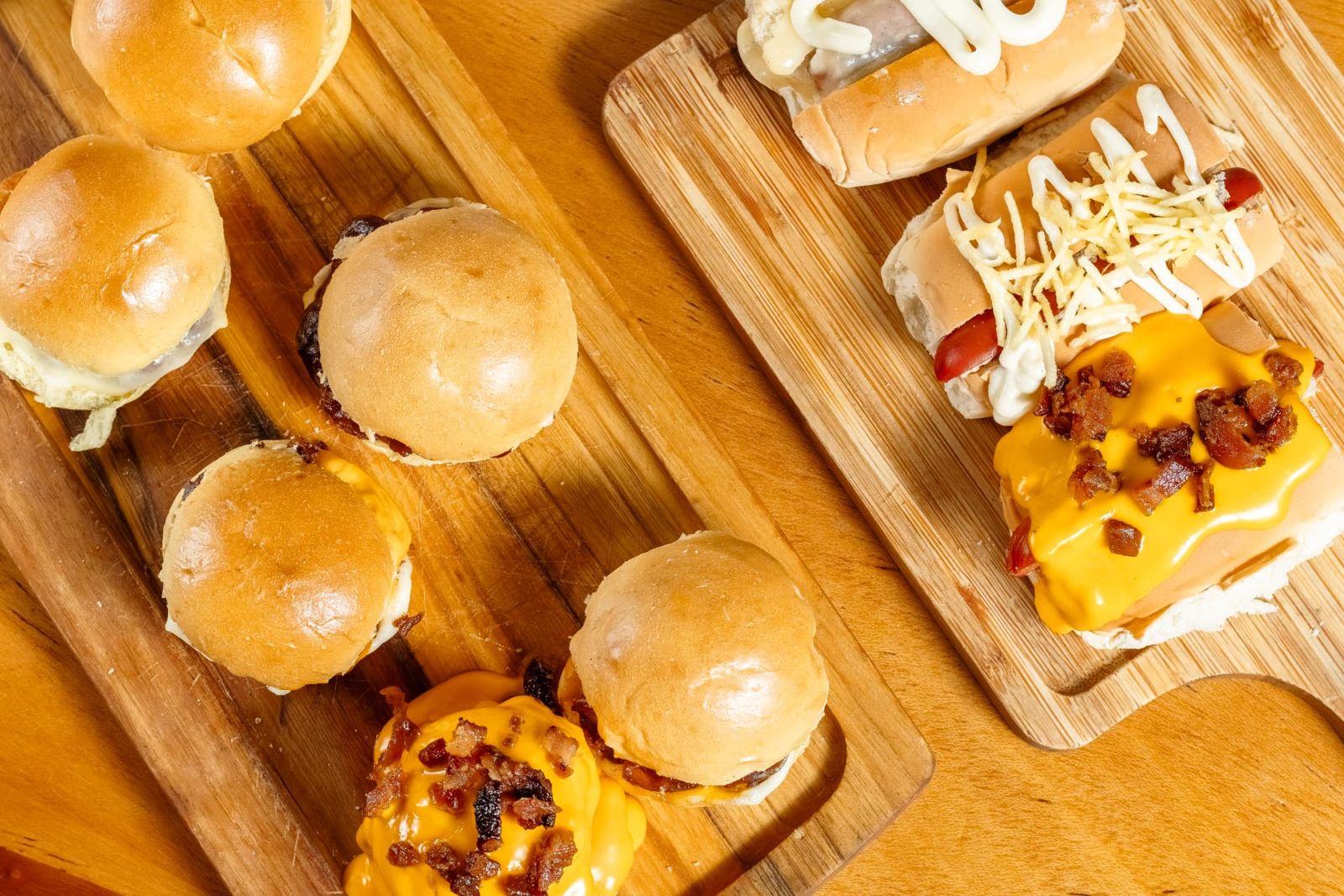 Mini burgers e mini hot dogs com cheddar e bacon na tábua